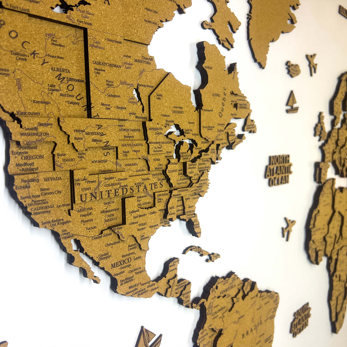 Layered laser-cut cork world map with dark brown edges and labeled continents