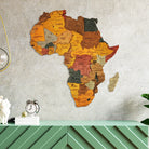 Wooden map of Africa on a textured wall with decorative items below.