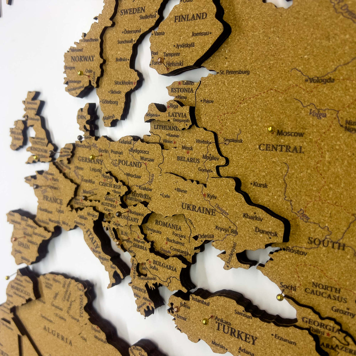 Layered laser-cut cork world map with dark brown edges and labeled continents
