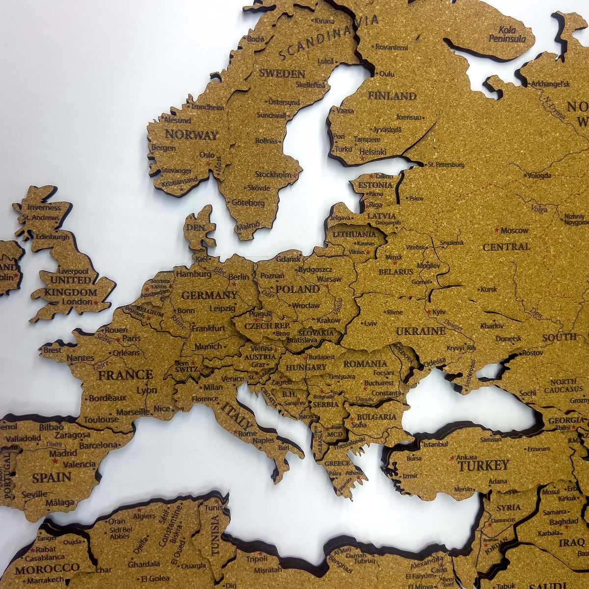 Layered laser-cut cork world map with dark brown edges and labeled continents