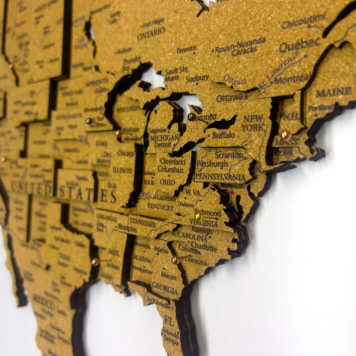 Layered laser-cut cork world map with dark brown edges and labeled continents